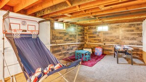 Ein Kellerraum mit einem Basketballkorb, einem Tisch und einem Stuhl.