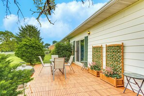 A wooden deck with outdoor furniture, a wooden planter with flowers, and a view of a green landscape. - 1 Mi to Hersheypark: Home w/ Patio in Hershey! (Hershey)