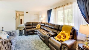 Ein Wohnzimmer mit einem Ecksofa, einem gemusterten Sessel und einer Lampe.