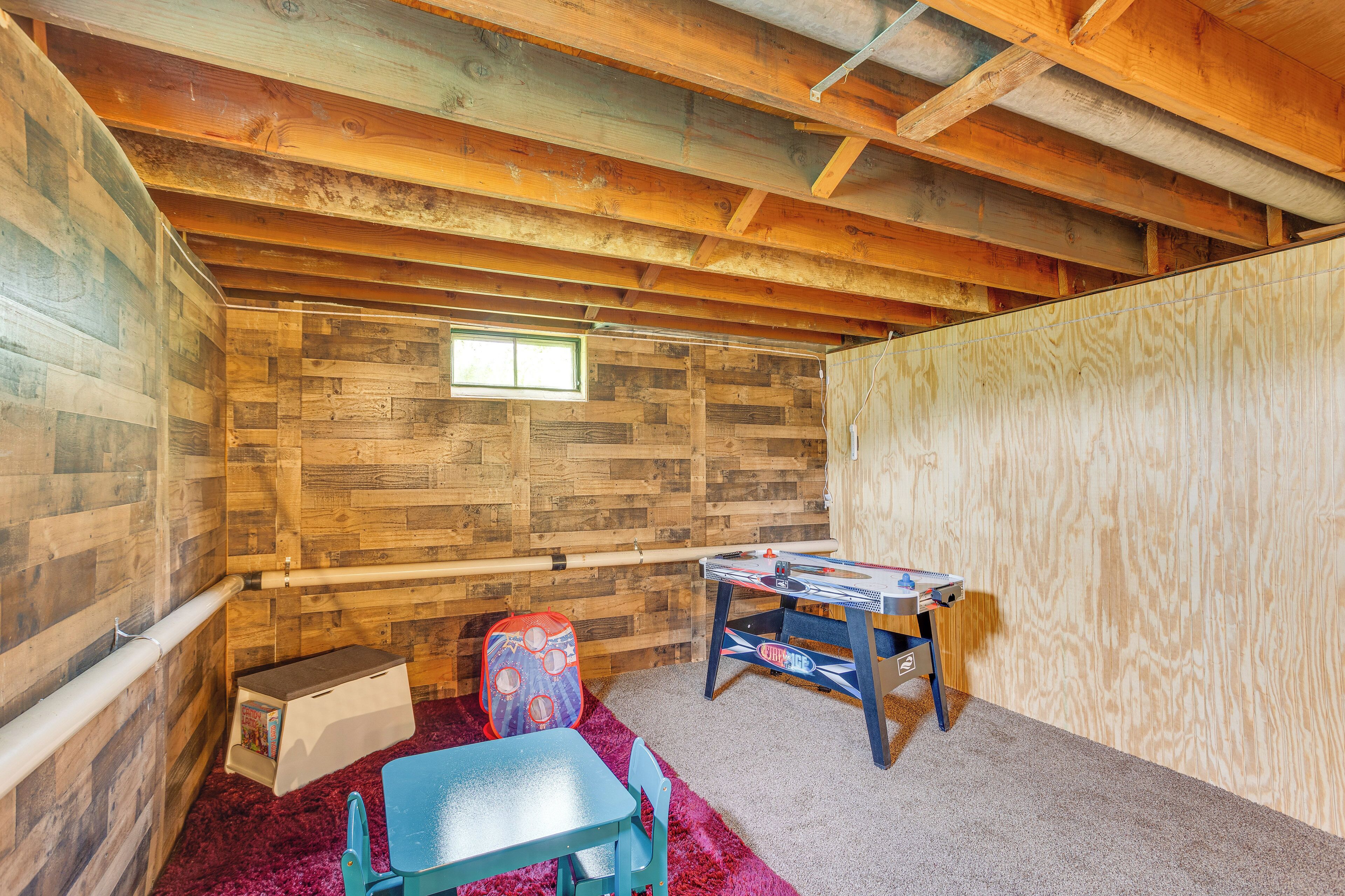 Une pièce avec un plafond en pente, des murs en bois, une petite fenêtre, une table, une chaise et une moquette rouge.