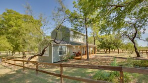 A two-story house with a porch, surrounded by a wooden fence and trees.