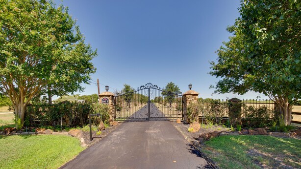 A gated driveway leading to a property with a clear sky above.