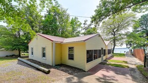 A yellow single-story house with a red roof, a front porch, and a view of a lake. - Riverfront Edenton Condo w/ Porch & Boat Ramp! (Edenton)