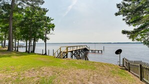 A lakeside view with a wooden dock, grassy area, and trees.