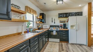 A modern kitchen with wooden countertops, black cabinets, a white refrigerator, and a microwave. - Charming Smiths Grove Home Near Cave Tours! (Smiths Grove)