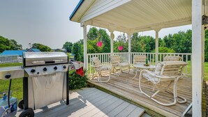 A covered outdoor patio with a grill, rocking chairs, and a white fence. - Charming Smiths Grove Home Near Cave Tours! (Smiths Grove)