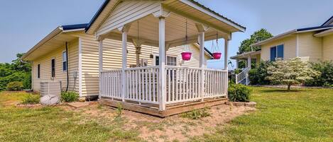 A single-story house with a covered porch, a small garden, and a clear sky.