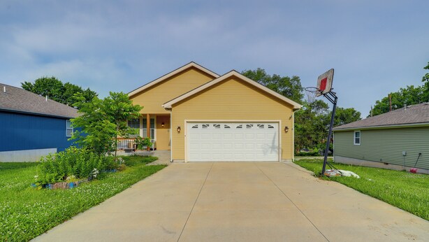 A residential house with a garage, a basketball hoop, and a well-maintained lawn. - Covered Balcony! Family-friendly Lansing Home (Lansing)