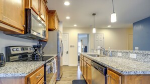 A modern kitchen with granite countertops, wooden cabinets, stainless steel appliances, and pendant lighting. - Covered Balcony! Family-friendly Lansing Home (Lansing)