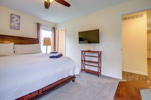 A bedroom with a large bed, a television on the wall, and a wooden nightstand.
