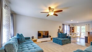 A living room with a ceiling fan, a TV, and two blue sofas. - Covered Balcony! Family-friendly Lansing Home (Lansing)
