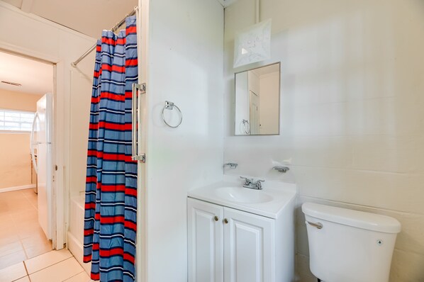Un baño con un lavamanos blanco, un inodoro y una cortina de ducha a rayas.