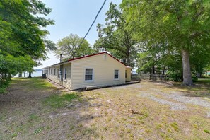 A single-story house with a red roof, a covered porch, and a gravel driveway. - Riverfront Edenton Condo w/ Porch & Water Views! (Edenton)