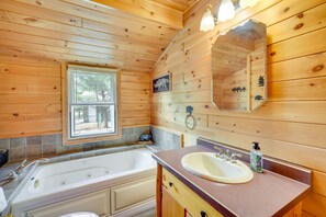 A wooden cabin bathroom with a bathtub, a sink, and a window.