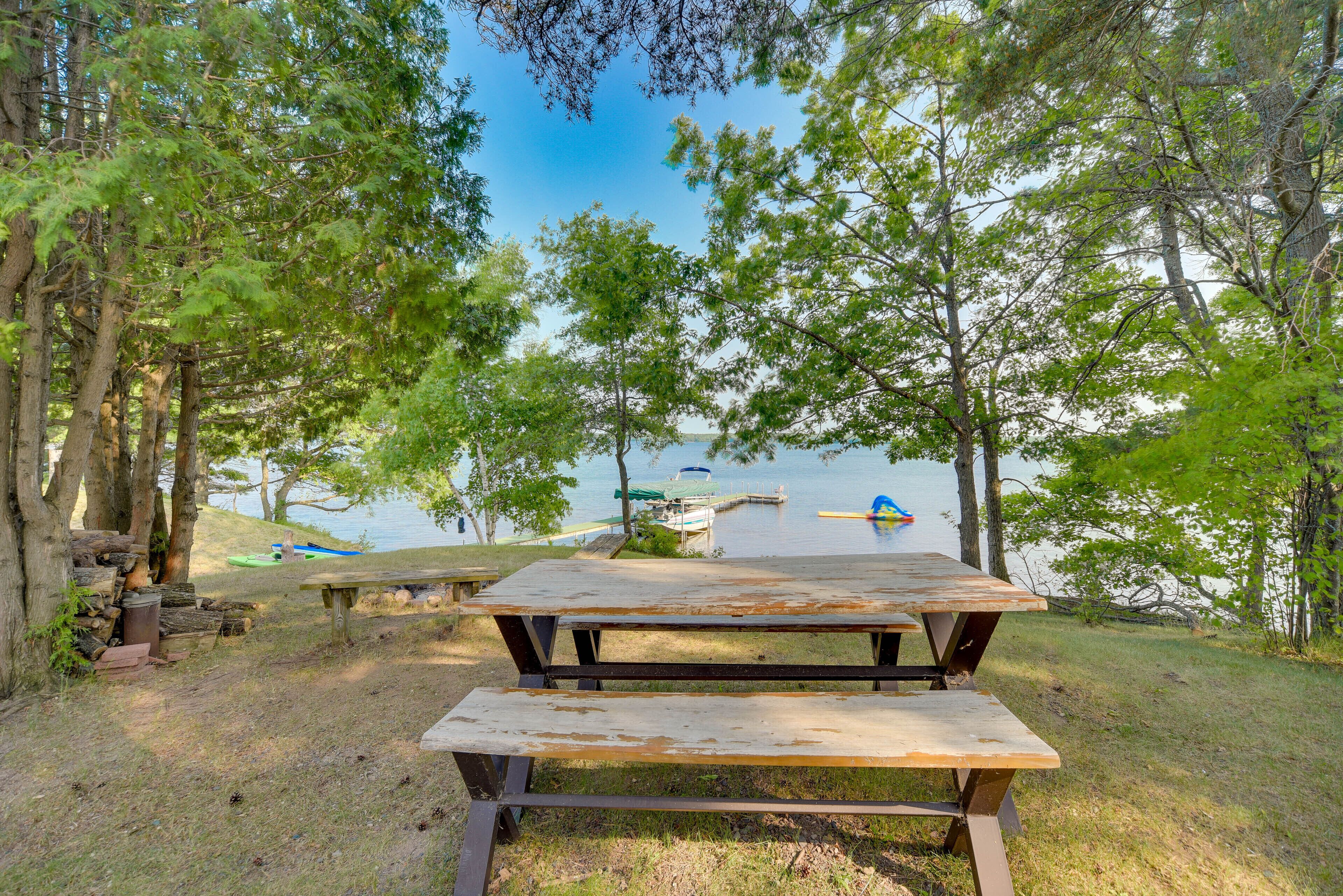 Ein Picknicktisch in einem bewaldeten Gebiet mit einem See und Booten im Hintergrund.