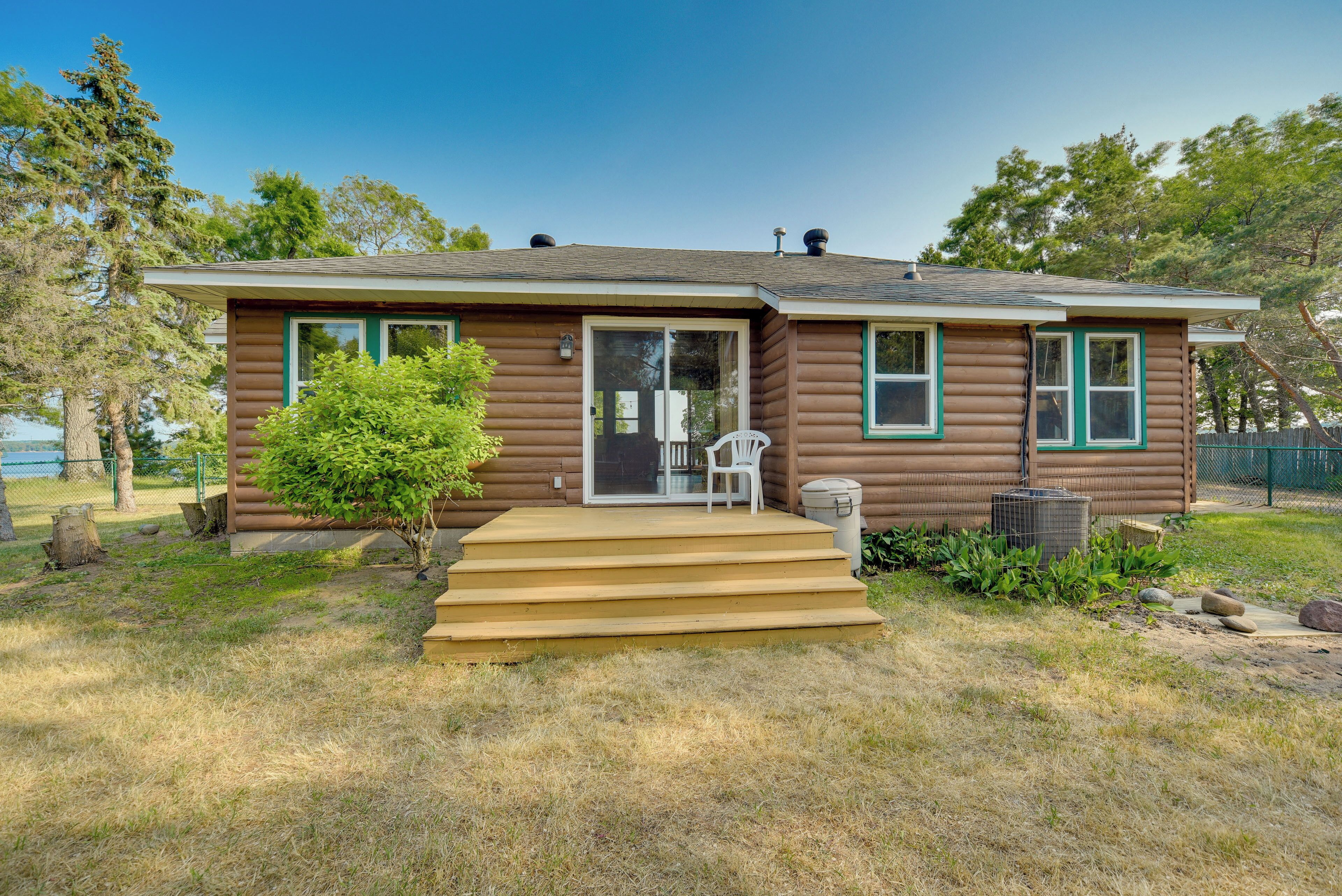 A log cabin with a front porch, a small garden, and a clear sky.