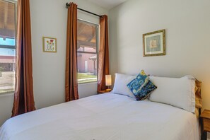 A neatly made bed with white linens, a bedside lamp, and a window with curtains. - Eloy Vacation Rental w/ Pool Access & Courtyard! (Eloy)