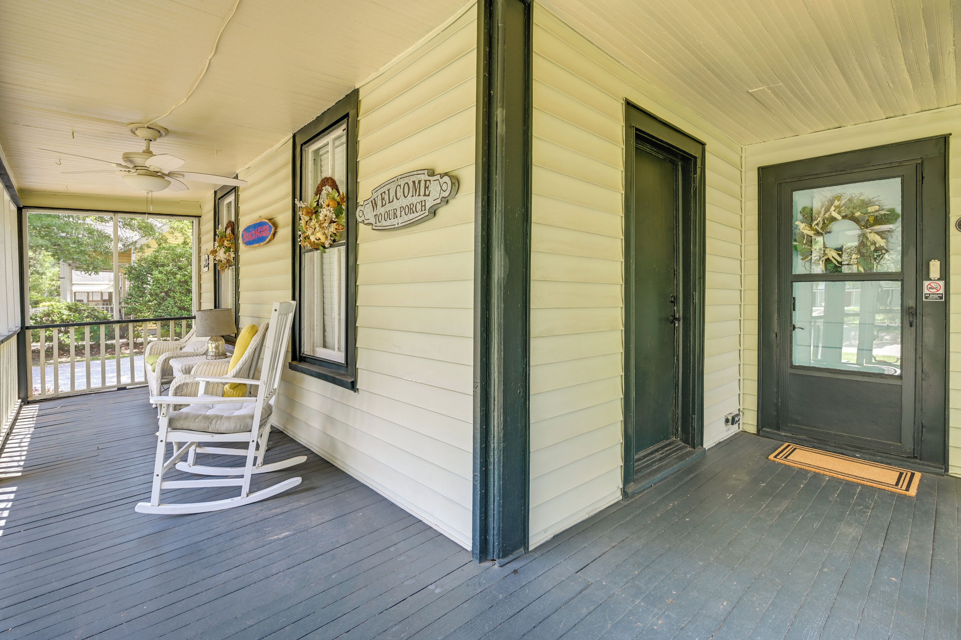 A porch with a rocking chair, a welcome sign, and a door with a wreath.