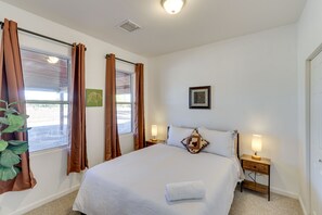 Relax in a serene space with a comfortable bed, a nightstand, and a window with a view.