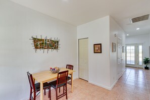A dining area with a table and chairs, a decorative wall piece, and a potted plant.