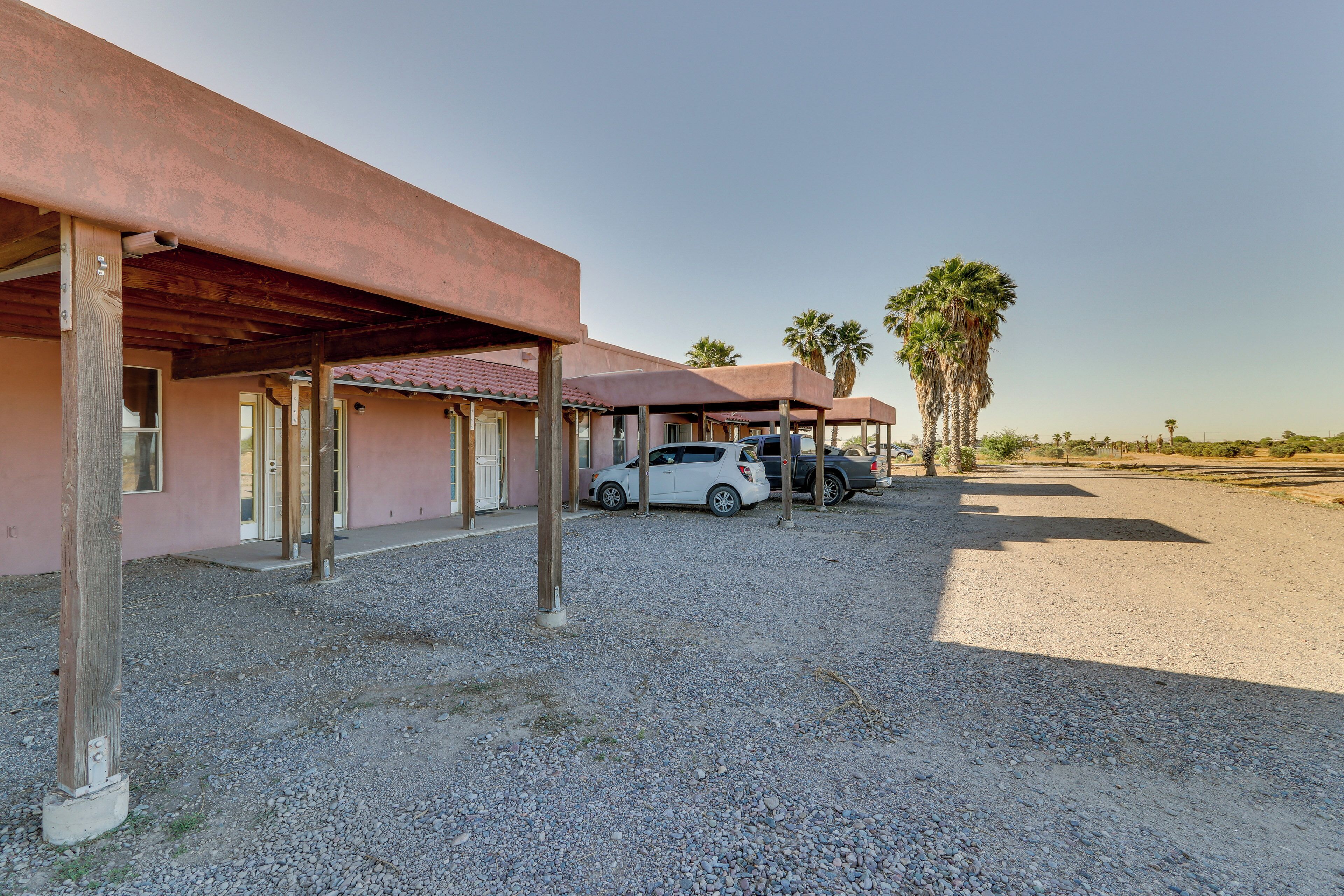 A building with a covered outdoor area, a gravel driveway, and parked cars.