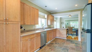 A kitchen with wooden cabinets, a dishwasher, and a refrigerator. - Cozy Michigan Retreat w/ Deck & Gas Grill! (Frankfort)
