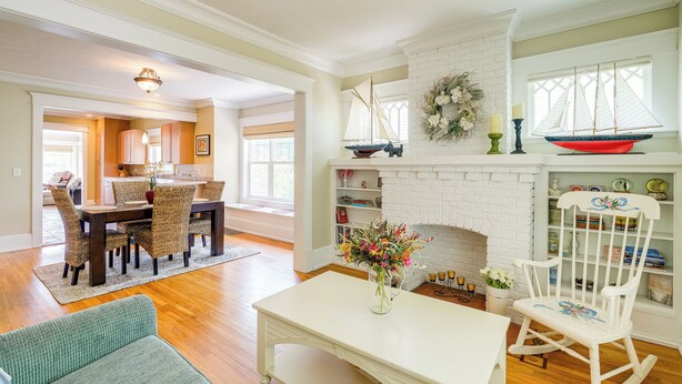 A spacious living room with a fireplace, a dining area, and a rocking chair. - Cozy Michigan Retreat w/ Deck & Gas Grill! (Frankfort)
