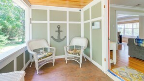 A room with two wicker chairs, a wooden ceiling, and a view of greenery outside. - Cozy Michigan Retreat w/ Deck & Gas Grill! (Frankfort)