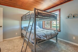 A bunk bed with a ladder, a window with a view, and a shelf with decorative items.