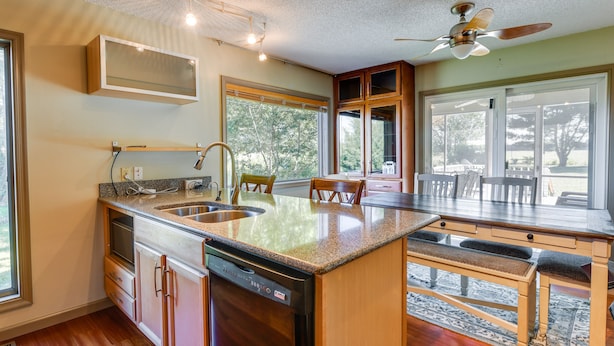 Una cocina moderna con una isla grande, lavavajillas integrado y un comedor con vistas al exterior.