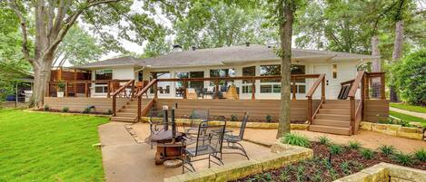A two-story house with a deck, outdoor seating, and a fire pit.