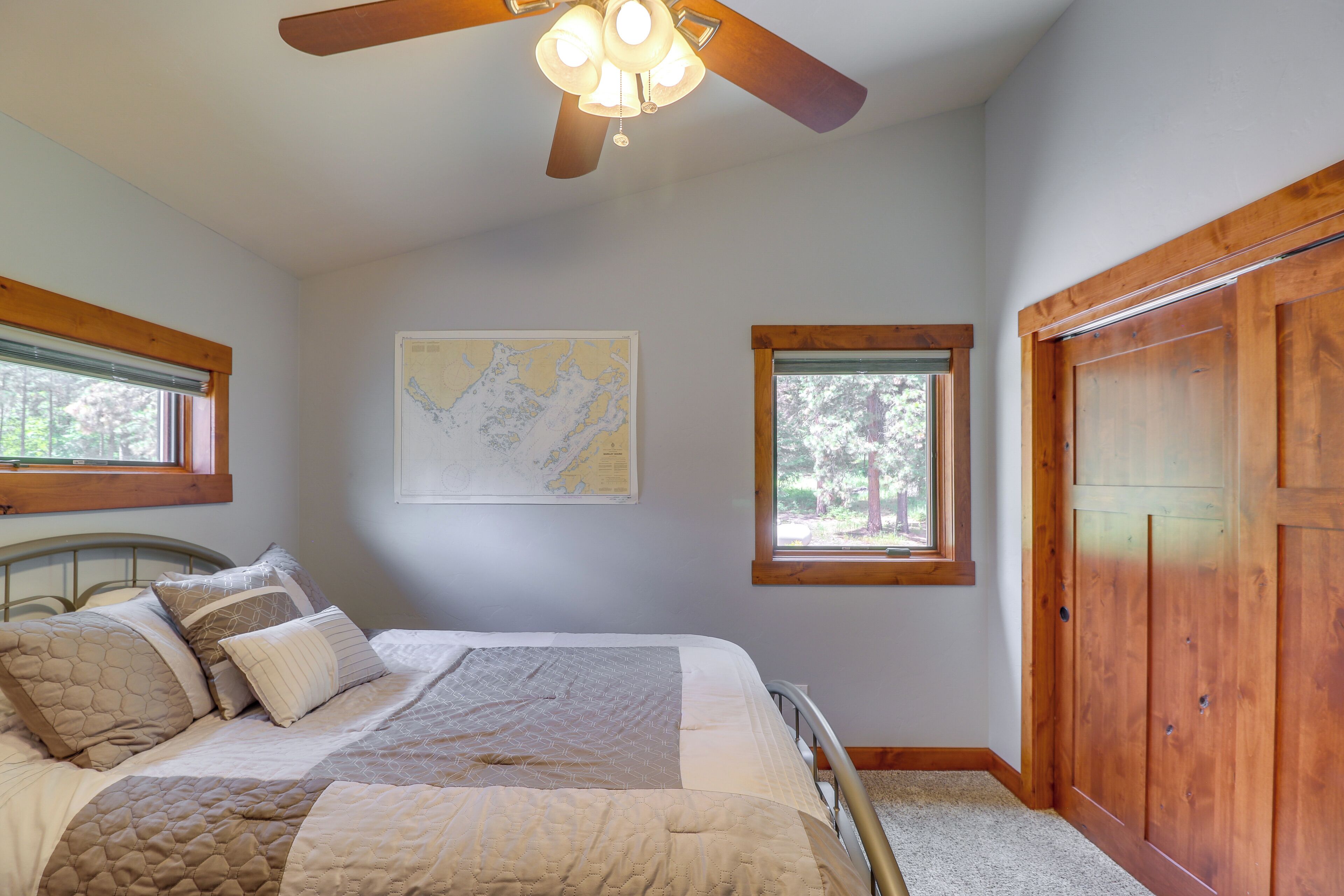 Un dormitorio con cama, ventilador de techo, un mapa en la pared y una ventana.