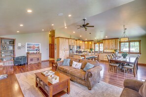 A spacious living room with a large brown sofa, a wooden coffee table, and a dining area with a wooden table and chairs. - Flathead Lake Base Camp in Somers: Lake View! (Somers)