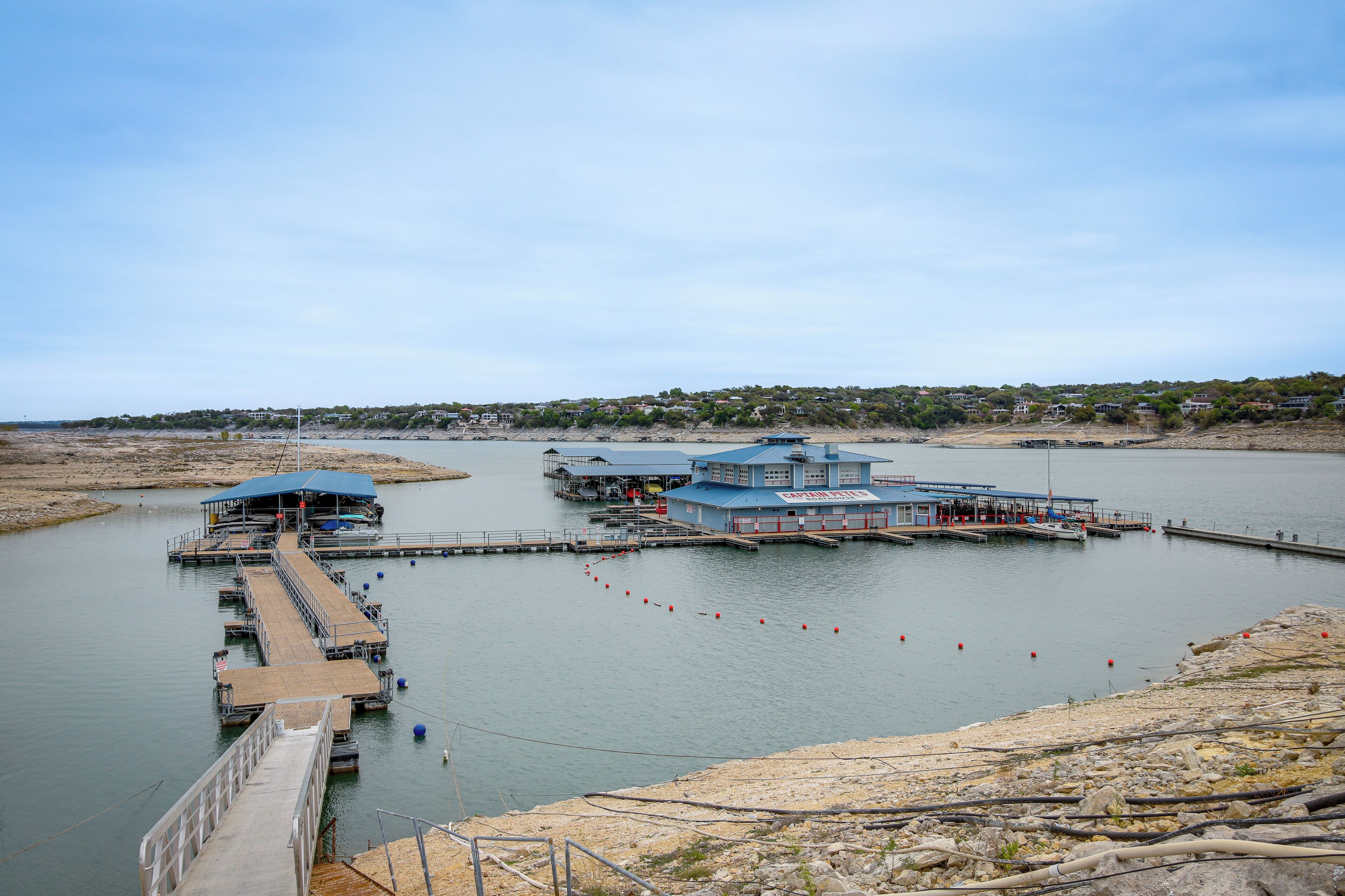 A marina with docks and boats, a pier, and a building with a blue roof.