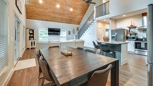 A spacious kitchen with a wooden ceiling, a dining area with a large table, and a staircase leading to an upper level. - Luxe Kentucky Cabin Rental ~ 36 Mi to Mammoth Cave (Cub Run)
