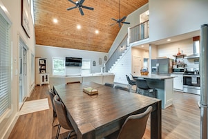 A spacious kitchen with a wooden ceiling, a dining area with a large table, and a staircase leading to an upper level.