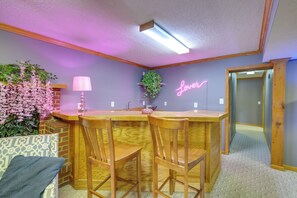 A kitchen with wooden bar stools, a neon sign, and a potted plant. - Hot Tub & Dock: Waterfront Bristol Area Retreat (Blountville)