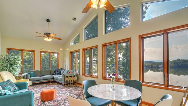 A spacious living room with a large window, a ceiling fan, and a dining area with a round table. - Waterfront Bristol Area Retreat w/ Boat Dock (Blountville)
