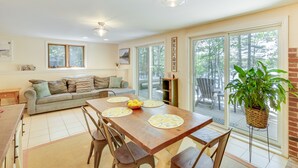 A spacious dining area with a wooden table, chairs, and a large window offering a view of the outdoors. - Waterfront Lake Arrowhead Home w/ Dock! (North Waterboro)