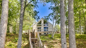 A two-story house with a wooden staircase leading to a balcony, surrounded by trees. - Waterfront Lake Arrowhead Home w/ Dock! (North Waterboro)