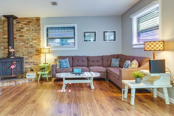 A cozy living room with a brick wall, a fireplace, a sofa, a coffee table, and a lamp.