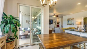 A modern kitchen with a wooden table, a potted plant, and a dining area with chairs.