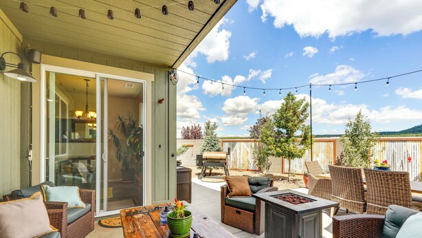 An outdoor patio with wicker furniture, a wooden table, and string lights.