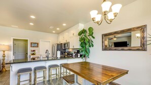 A kitchen with a wooden island, bar stools, a chandelier, and a large mirror.
