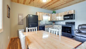 A kitchen with wooden cabinets, a black refrigerator, a microwave, and a stove. - Cozy Lake Wissota Escape w/ Community Dock! (Chippewa Falls)