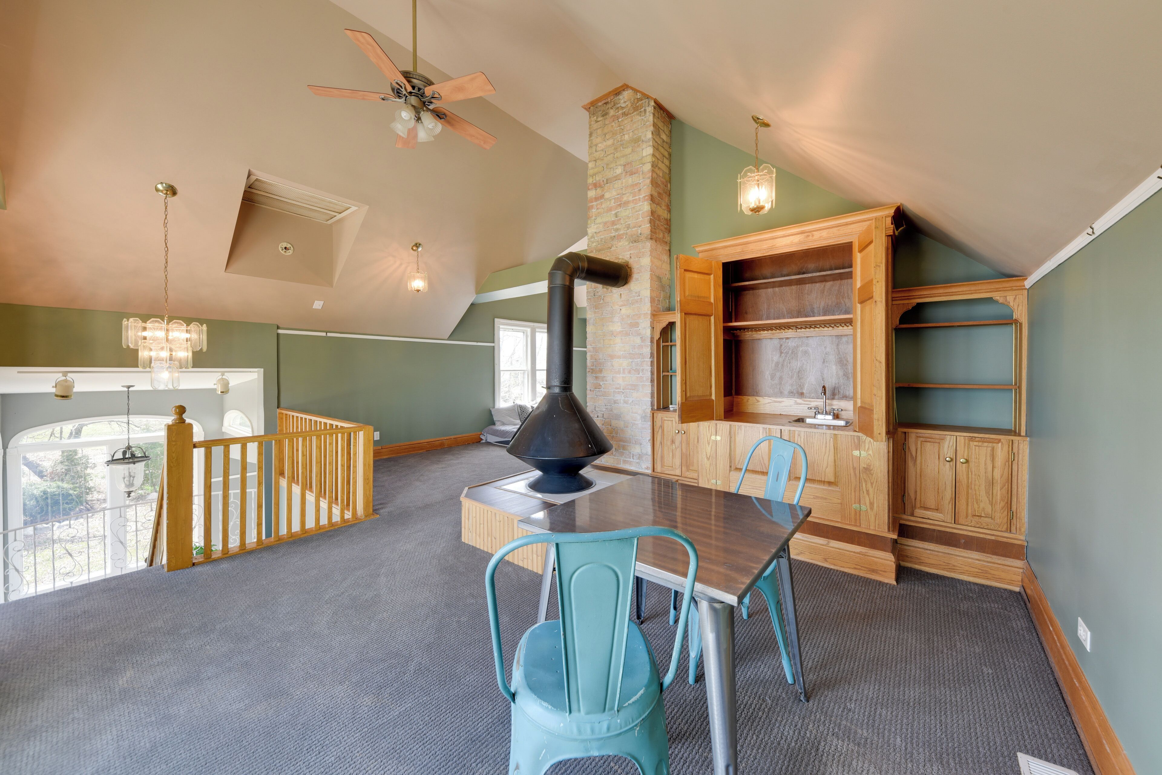 Ein geräumiges Schlafzimmer im Loft-Stil mit hoher Decke, integriertem Kamin, Essbereich mit Tisch und Stühlen sowie Blick ins Freie.