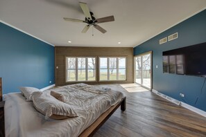A bedroom with a large bed, a ceiling fan, and a TV mounted on the wall. - Lake Michigan Vacation Rental w/ Private Beach! (Racine)