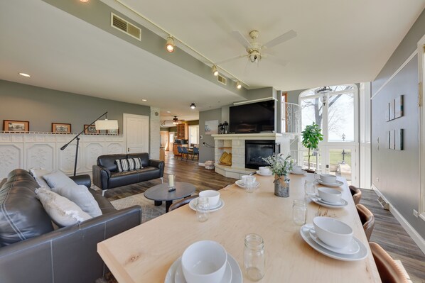 A spacious living room with a dining area, a fireplace, and a television. - Lake Michigan Vacation Rental w/ Private Beach! (Racine)
