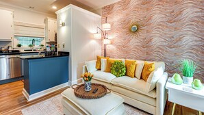 Een moderne keuken met een blauw eiland, een witte bank met gele kussens en een decoratieve wand met een golvend patroon.