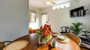 Een eetruimte met een houten tafel, een bloevas en een plafondventilator.